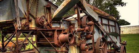 A duplicate machine, rusted and worn-out, sitting abandoned in a field.