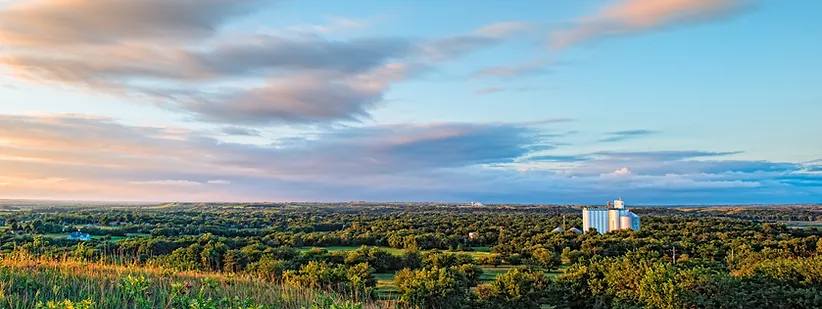Sunset over a hill with trees and a white building.