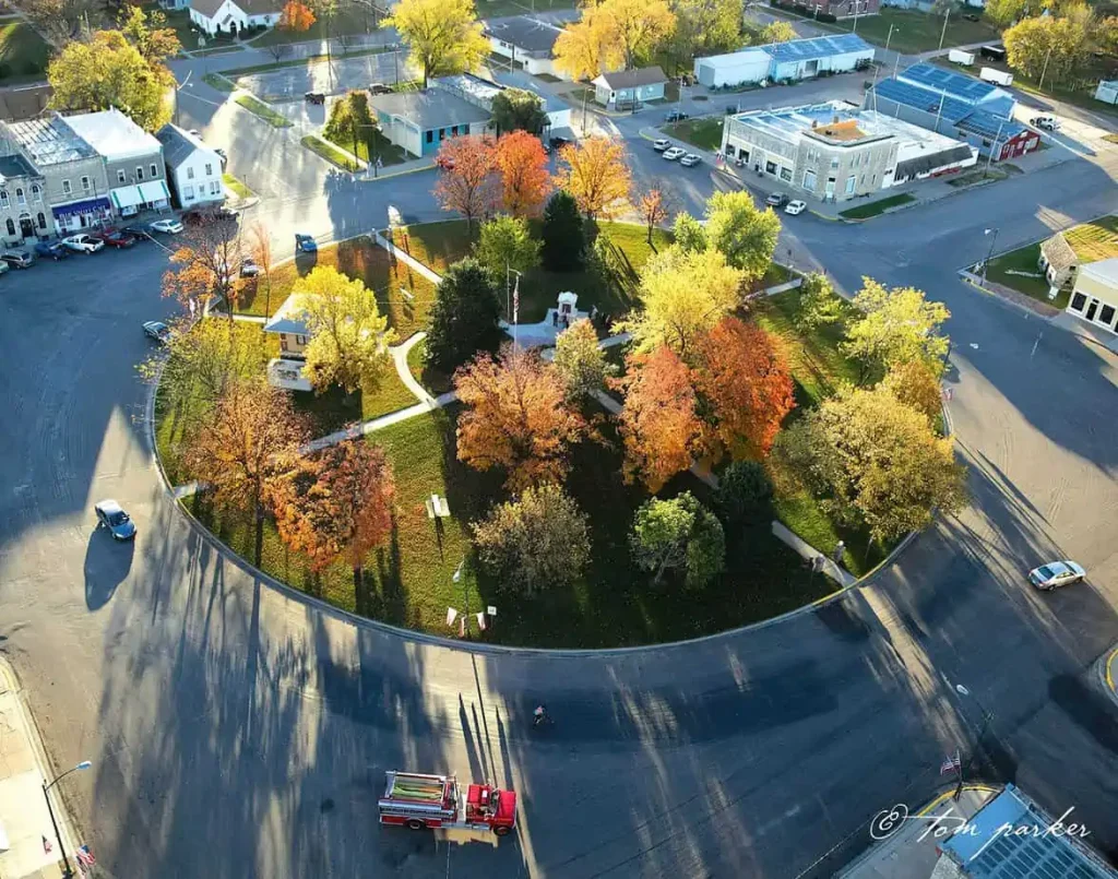Aerial view of a town square with colorful autumn trees and a fire truck on the road.